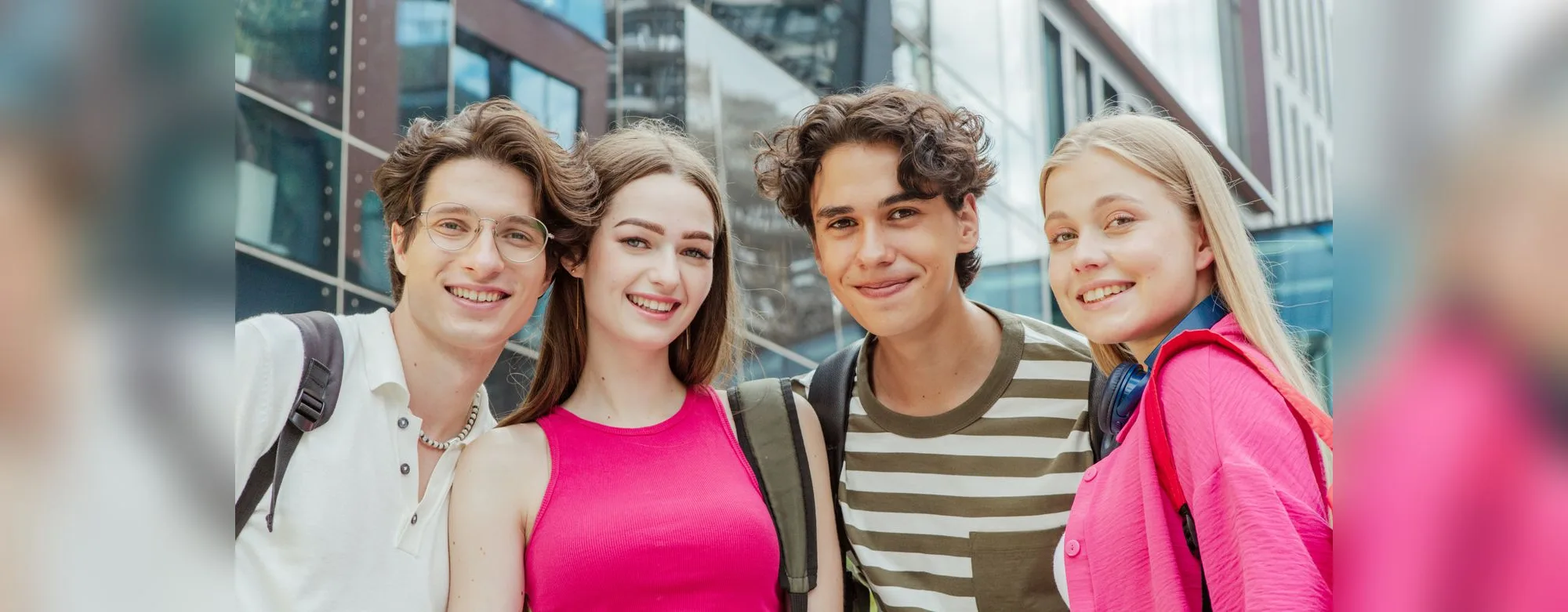 Four smiling students standing together outdoors