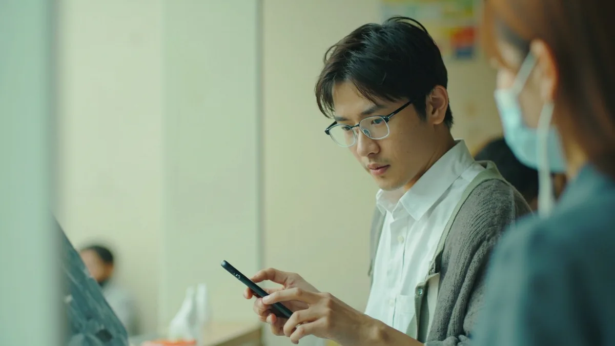 A traveler holds their phone and charger while looking for an electrical outlet, illustrating “can I charge my phone here” in Chinese: 手机能充电吗？ (shǒujī néng chōngdiàn ma?)