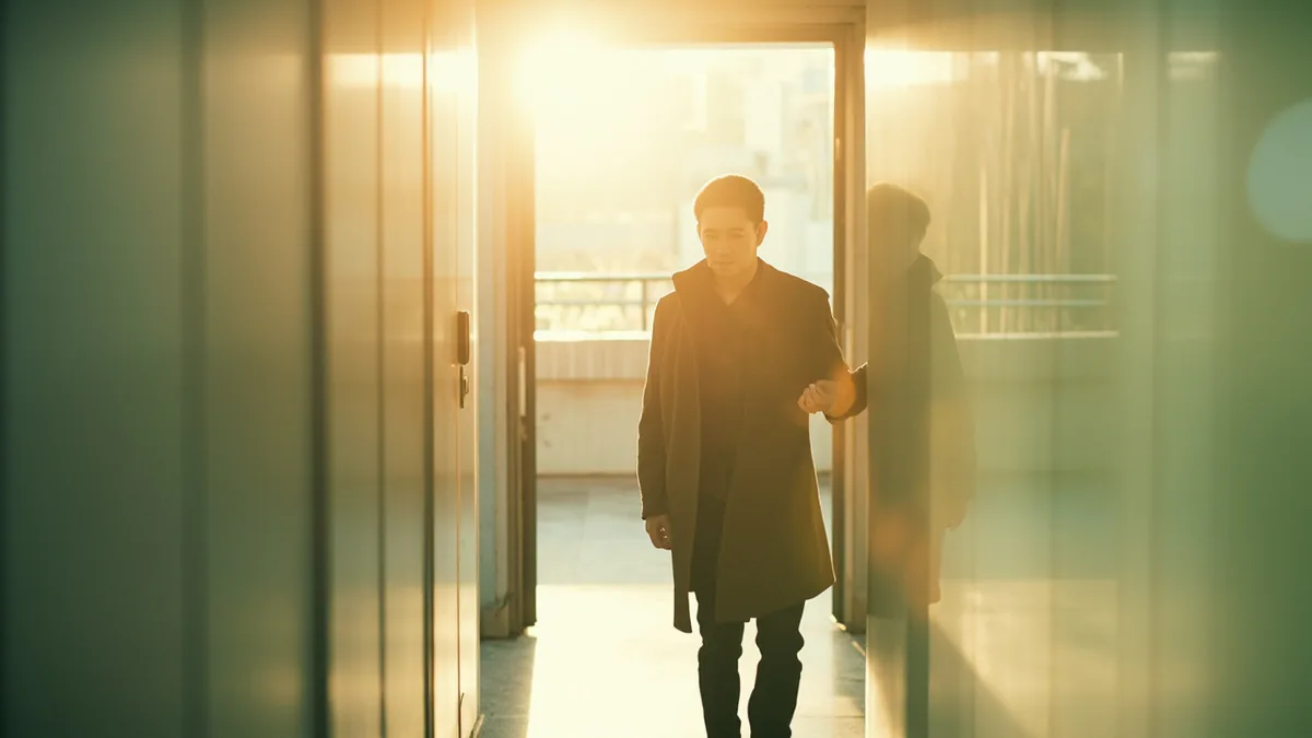 A worker leaves the office as evening light falls, illustrating “I get off work at six” in Chinese: 我六点下班 (wǒ liù diǎn xiàbān)