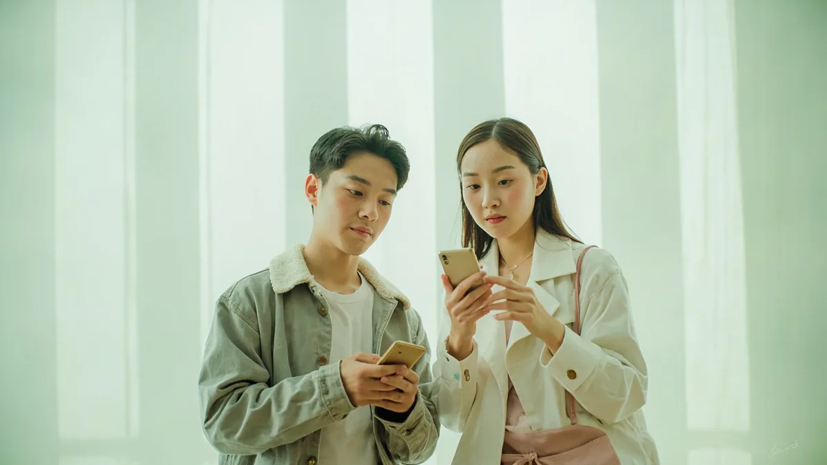 Two friends exchange contact information using their phones, illustrating “I'll message you on wechat” in Chinese: 我给你发微信 (wǒ gěi nǐ fā wēixìn)
