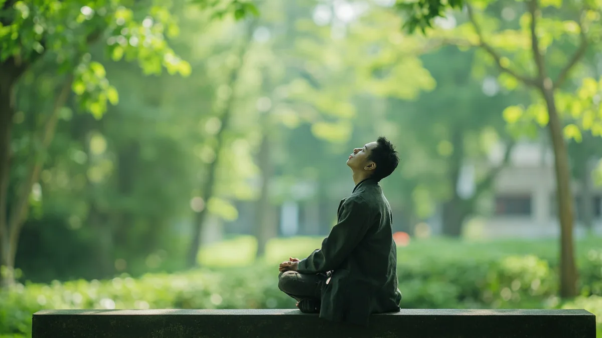 A person sits calmly in a quiet park garden, illustrating “inner peace” in Chinese: 内心平静 (nèi xīn píng jìng)