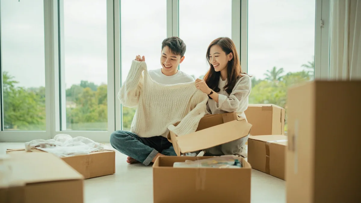 A young adult joyfully unboxes several packages from online shopping, illustrating “singles' day” in Chinese: 光棍节 (Guānggùnjié)