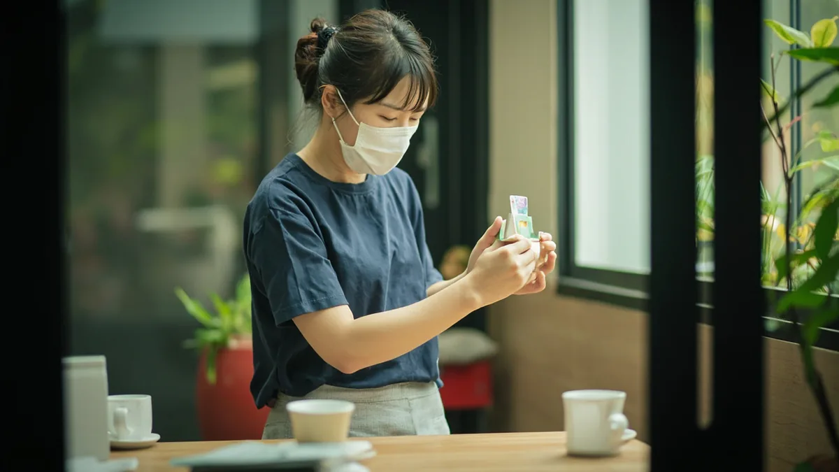 A person gently turns a simple display to indicate a business is closed, illustrating “we're closed today” in Chinese: 今天休息 (jīntiān xiūxi)